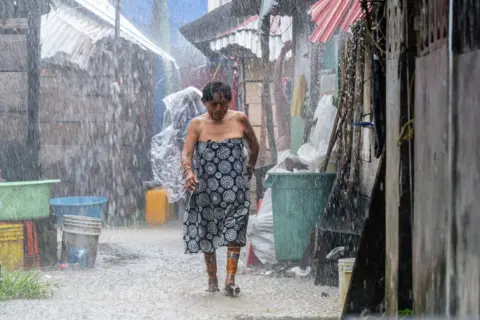 Getty Images A Guna Indigenous woman walks under the rain on the island of Carti Sugtupu, in the Indigenous Guna Yala Comarca, Panama, in the Caribbean Sea, on August 28, 2023.