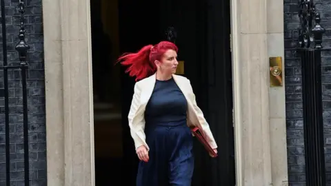 Getty Images Woman with red hair walking and holding red file