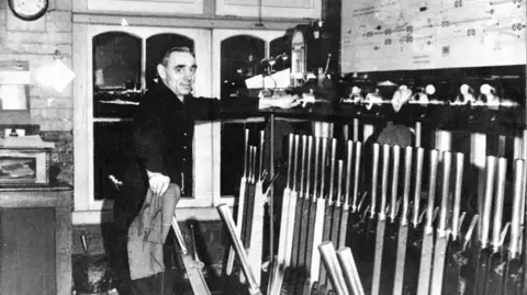 Haslemere Signal Box Trust A black and white image of a man in a signal box pulling levers