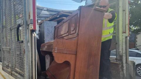 The piano being loaded on to a council van