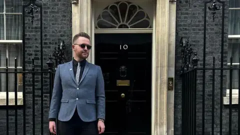 James Clarke James Clarke, wearing a jacket and dark glasses, stood outside the door of 10 Downing Street