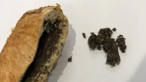Beef Wellington cut open with filling exposed on left of image and some of the filling out on the right