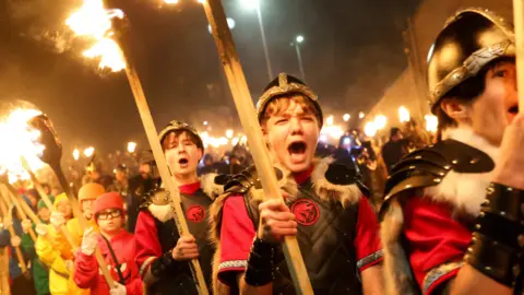 Reuters The Junior Jarl Squad takes part in the junior procession. The  children are in Viking costumes and carrying flaming torches. Some of them are shouting