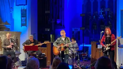 Mark Hutchings Glen Matlock and three other musicians perform with Kevin Brennan when he was an MP in St John's Church in Canton, Cardiff. The background is lit blue