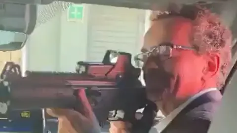 Man looking down sights of gun in car