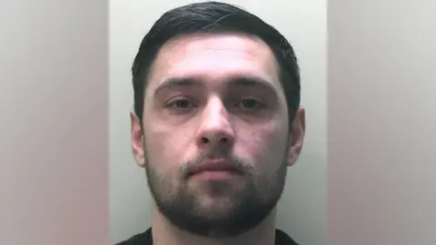 States of Jersey Police A custody image of Dylan John Pounds, a man with short dark hair and facial hair.