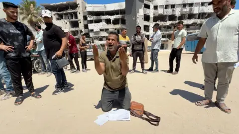A man waiting for a medical evacuation kneels outside al-Shifa hospital in Gaza City, northern Gaza