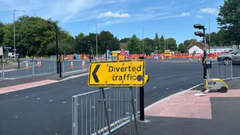 View of the junction into North Walsham which is covered in orange cones, traffic barriers, temporary traffic lights and diversion signs.