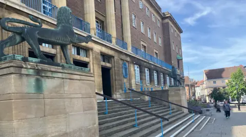 Owen Sennitt/BBC A lion statue can be seen on a plinth next to a staircase that leads to Norwich City Hall