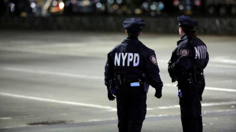 NYPD cops stand on street at night