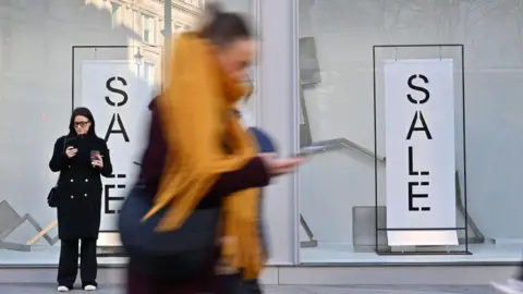 Getty Images Two women outside a shop having a sale