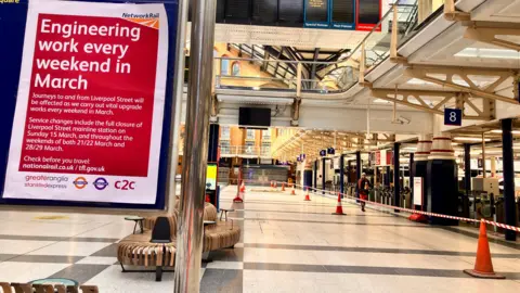 An empty station with cones and red safety tape in place alongside signage explaining engineering work closures.
