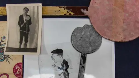 Hanson's Auctioneers Sebuah prop tahap sekitar tahun 1940 dalam bentuk lollipop yang dimakan sebagian, digunakan oleh Eric Morecambe muda dalam rutinitasnya "Pemuda mengambil busur"