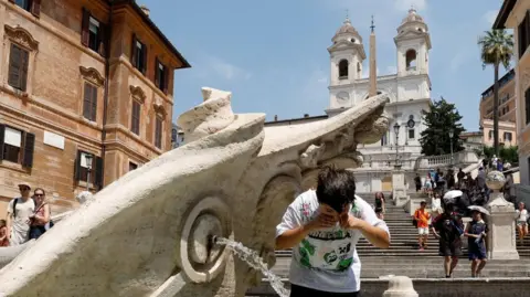 A boy cools off at the Barcaccia fountain near the Spanish steps during a heatwave, as temperatures are expected to rise further in the coming days, in Rome, Italy August 3, 2026.