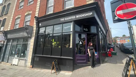 Monika is standing in front of the The Haunted Bookshop. 