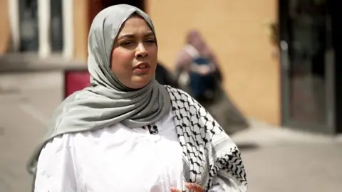 Shahmina in white blouse and grey headscarf.