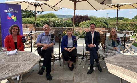 Five candidates sit outside at a pub