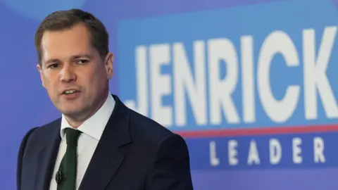 PA Media Tory leadership hopeful Robert Jenrick speaks to supporters as he stands in front of a sign saying "Jenrick for leader" during his Conservative Party leadership campaign launch at the YMCA Community and Activity Village, in Newark