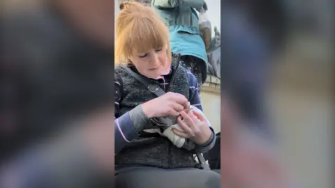 Woman with red hair holding a pigeon.