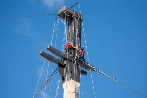 NMRN Two workers at the top of one of the masts.