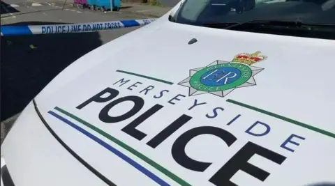 The bonnet of a Merseyside Police car bearing Merseyside Police's logo against a white background