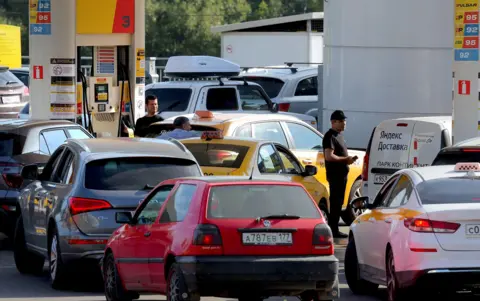EPA Cars line up at a petrol station in Moscow on Thursday