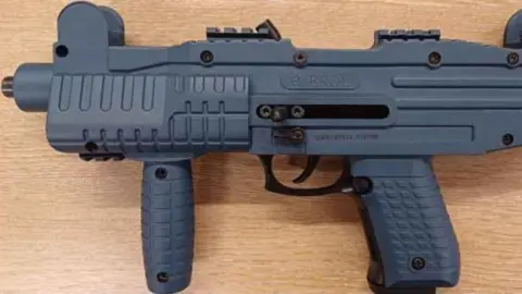 Nottinghamshire Police A side view of a blank firing firearm sat on a wooden effect surface.