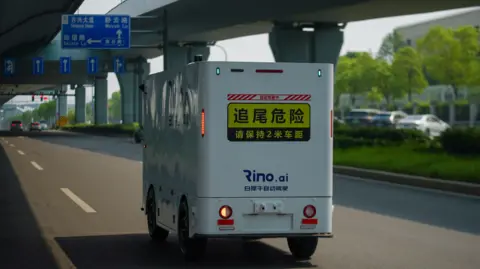 BBC/Joyce Liu A Rino AI delivery truck cruises on the road in China