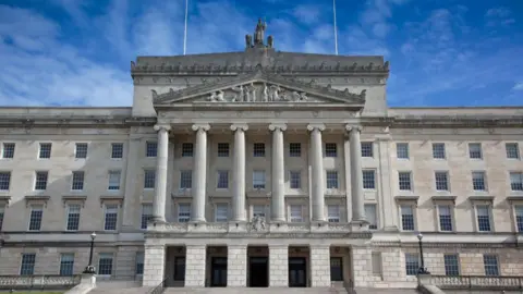 Getty Images The front of Stormont from the outside. The building is cream stone and has pillars and engravements on it.