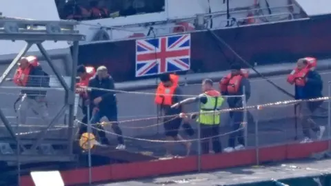 PA MEDIA Men walking onto a dock 