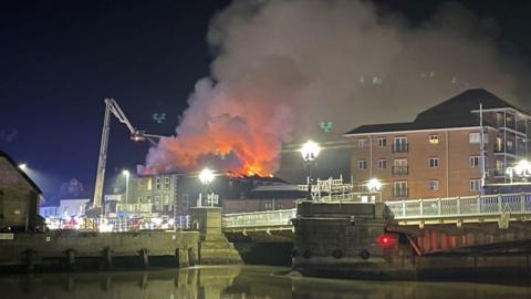 The Haven Bridge pub on fire, with the water at Great Yarmouth in the foreground