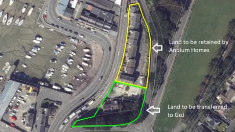 Andium Homes An aerial photo of the Haut du Mont site. The north part of the site is outlined with yellow and an arrow points to it labelled: Land to be retained by Andium Homes. The area to the south of this one is outlined in green with an arrow pointing to it labelled: Land to be transferred to GoJ.
To the left of the site is a harbour with about 20 small boats moored up. To the right of the site is a green field. 