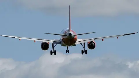 A red and white plane, with blue sky and clouds in the background