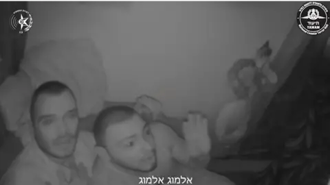 Israeli police body camera footage shows Andrei Kozlov (left) sitting on a sofa, looking in pain