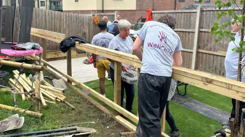 A team of volunteers putting together a fence with materials scattered