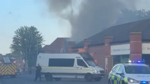 Jacob Marshall Smoke rising from old brick building with emergency services in attendance