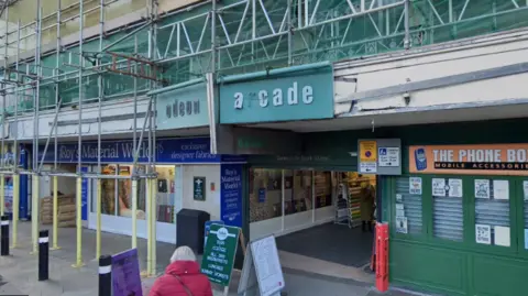 The entrance to Odeon Arcade with a green sign above the entry. Scaffolding can be seen above the ground floor.