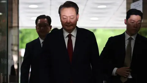 AFP via Getty Images Yoon Suk Yeol (C) arrives at a court to attend a hearing to review his arrest warrant requested by special prosecutors, in Seoul on July 9, 2025. 