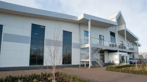 David Lloyd The front of a fitness club. It is white with large windows. There is a sign that says "Shrewsbury Club".