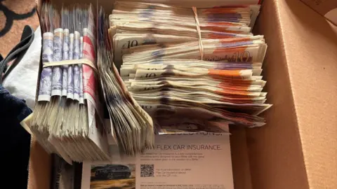 Cambridgeshire Constabulary Bundles of cash in a brown shoebox, including £10, £20 and £50 notes.