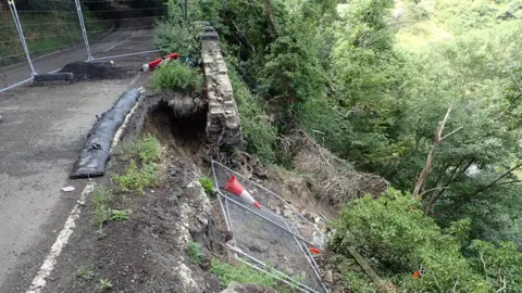 Dalton Bank Road showing the landslip with some safety barriers which have fallen over