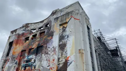 The Littlewood building with a mural painted on the front and scaffolding on the side