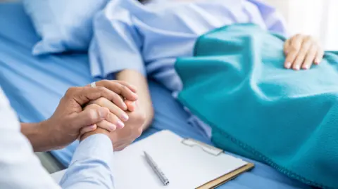 Getty Images A woman holding a patient's hand
