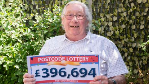 Alan Mizon holding a sign showing he has won £396,694