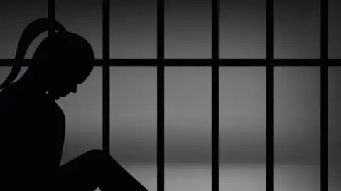 Getty Images shadow graphic shows the outline of a woman with a ponytail behind prison bars