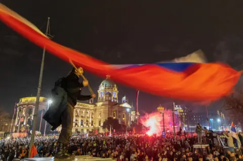 Reuters A man waves a Serbian flag as students and anti-government demonstrators gather in front of the parliament building during a protest