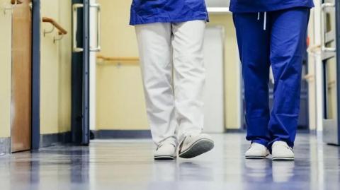 Two healthcare workers walking in a corridor