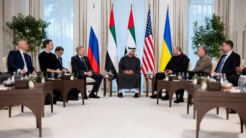 Reuters A handout photo released by the UAE Presidential Court shows UAE President Mohamed bin Zayed Al Nahyan (centre), meeting Kirill Budanov, Director of the Office of the President of Ukraine (R), Steve Witkoff, United States Special Envoy (2-R), Rustem Umerov, Secretary of the National Security and Defense Council of Ukraine (3-R), Igor Kostyukov, Chief of the Main Directorate of the General Staff of the Russian Armed Forces (3-L), and Jared Kushner (2-L) during UAE-hosted trilateral talks between the United States, Russia and Ukraine at Al Shati Palace in Abu Dhabi. The participants are sitting in a semi-circle with the Russian, UAE, US and Ukrainian flags behind them. 