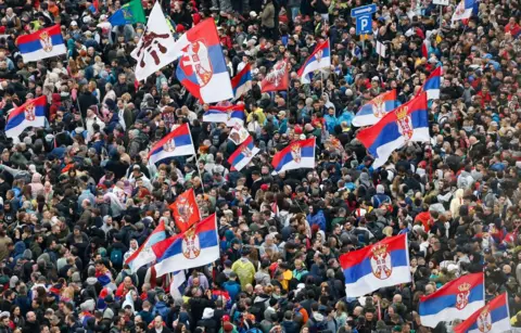 Getty Images Sea of protesters holding Serbian flags while marching into Belgrade on March 15, 2025.