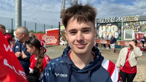 Matt Dean / BBC Jake Law he has short black hair and is wearing dark blue hooded top